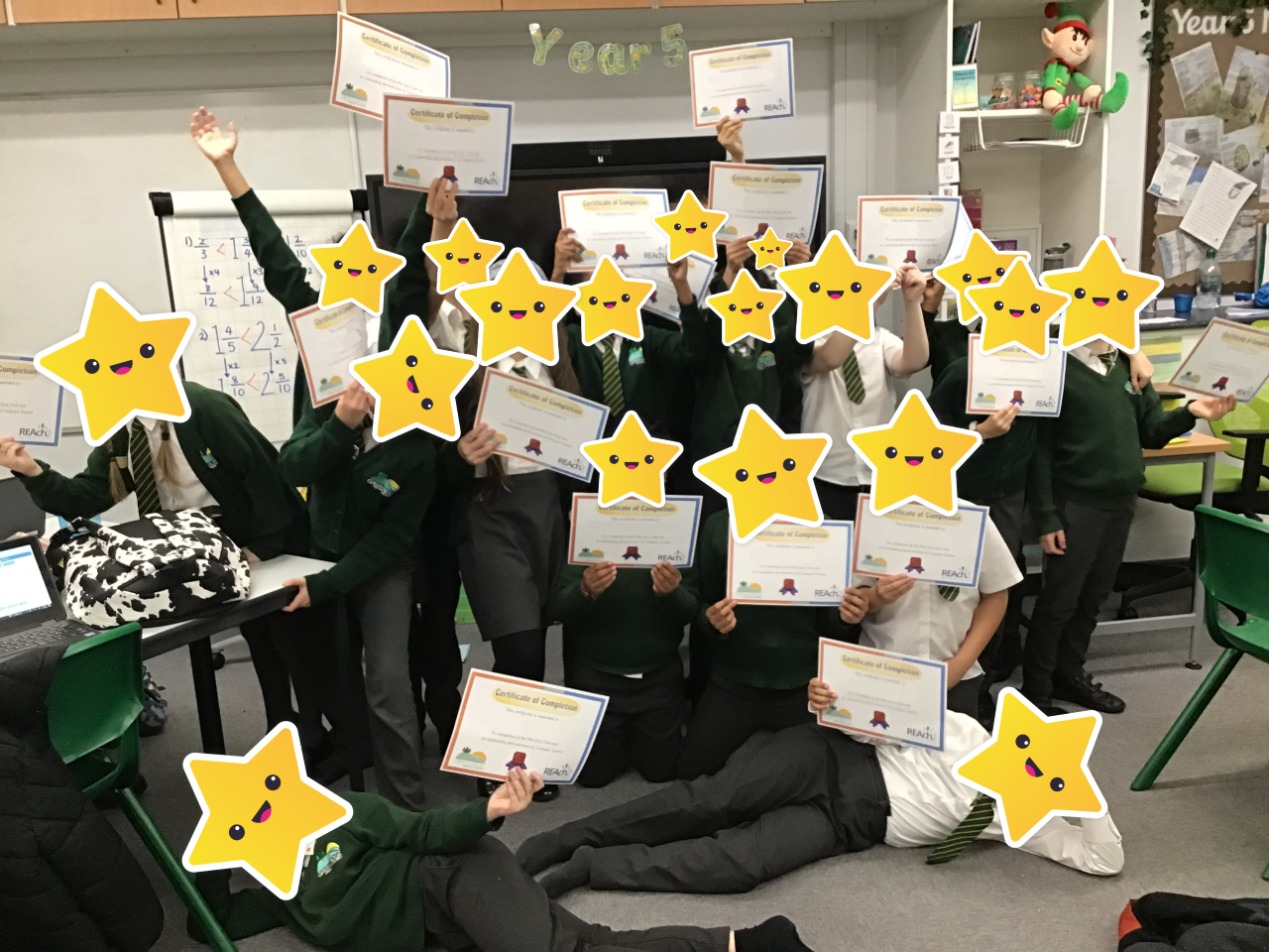 18 children with cartoon-style stars covering their faces proudly holding up certificates after compleating the Mini Devs Club.