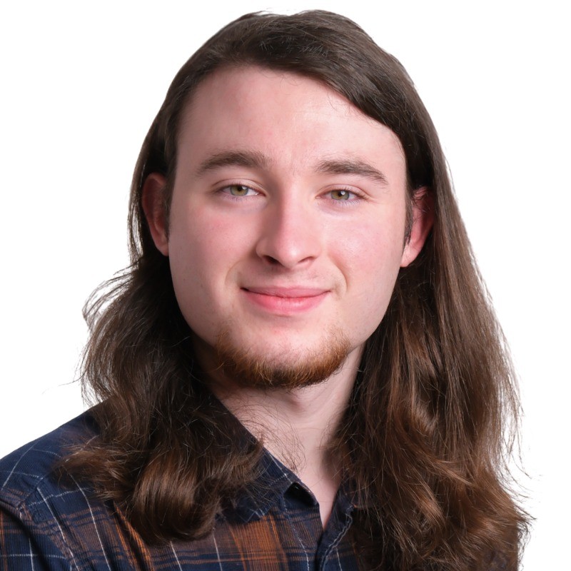 Brown-haired man wearing a shirt. The image is within a circular frame